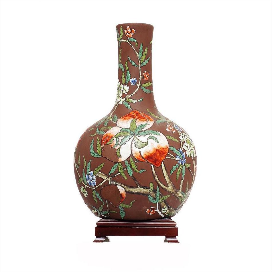Brown ceramic Chinese vintage flower vase with long neck, floral and fruit design, on wooden stand.