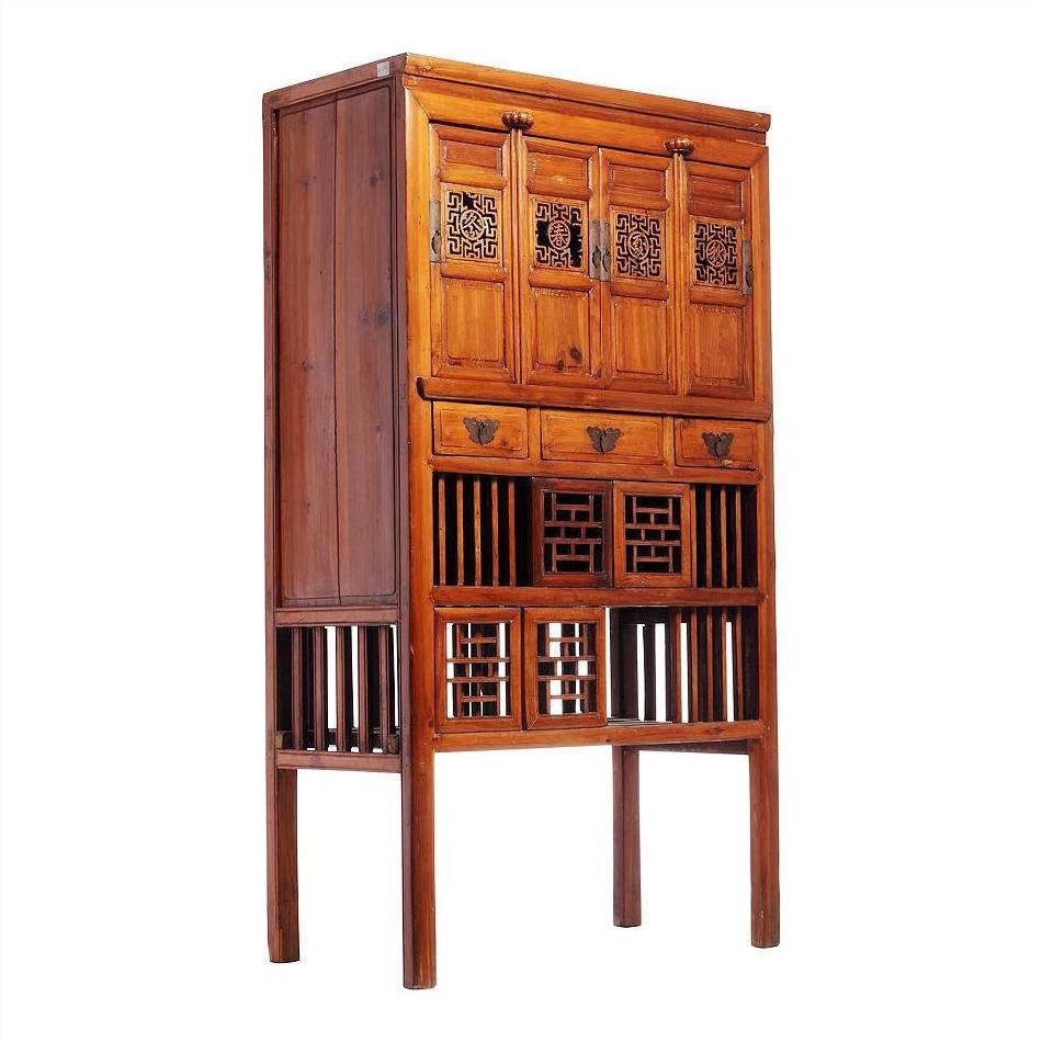 Dark wood Chinese cabinet with intricate carved doors, drawers, and lower section open latticework, front view.
