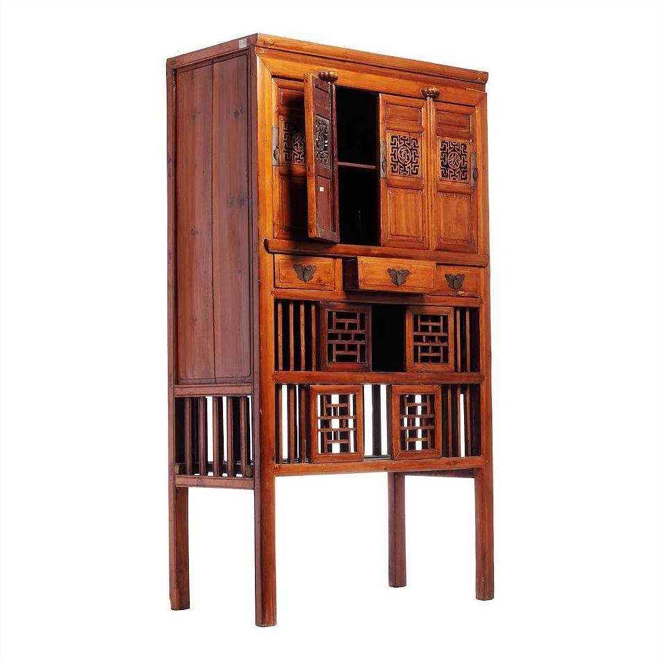 Dark wood Chinese cabinet with carved fretwork, butterfly hardware, drawers, and open slatted shelves.