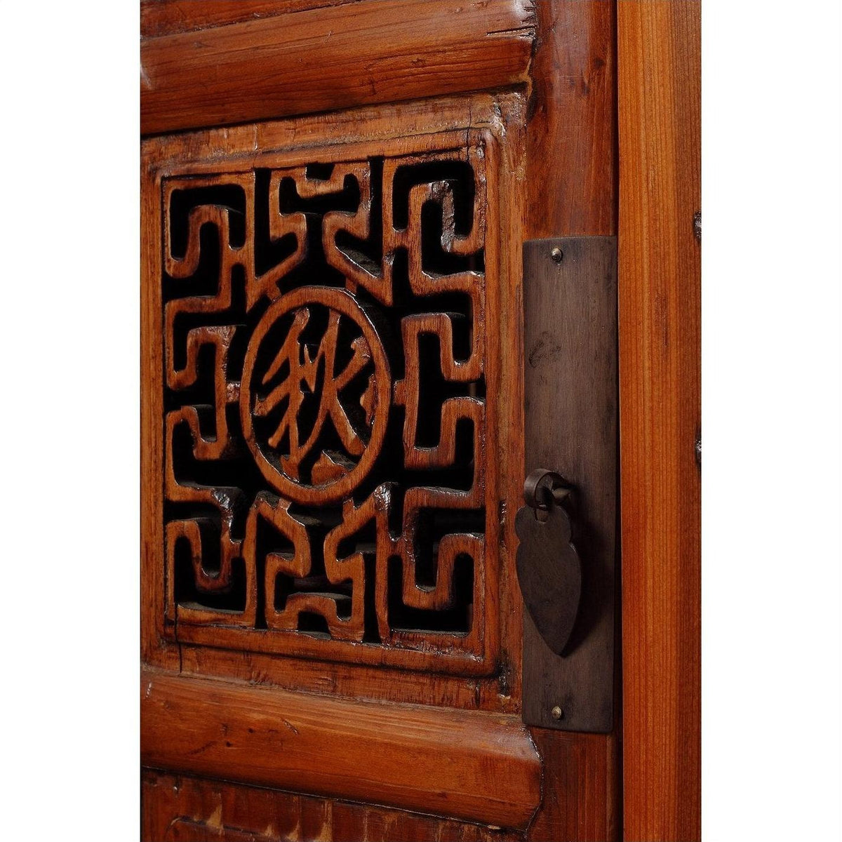 Close-up of dark wood Chinese cabinet with geometric fretwork carvings, butterfly hardware, and circular central symbol.