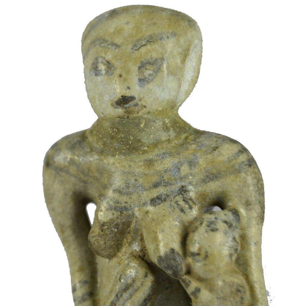 Brown glazed terracotta miniature fertility doll holding child, simple features, textured surface, close-up.