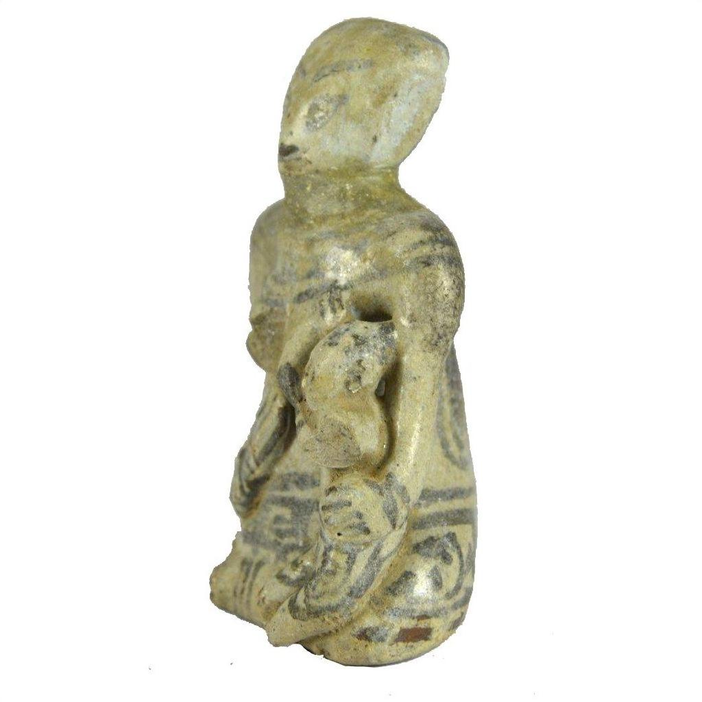 Brown glazed terracotta fertility doll with faded patterns, seated holding a small figure in its lap, close-up.