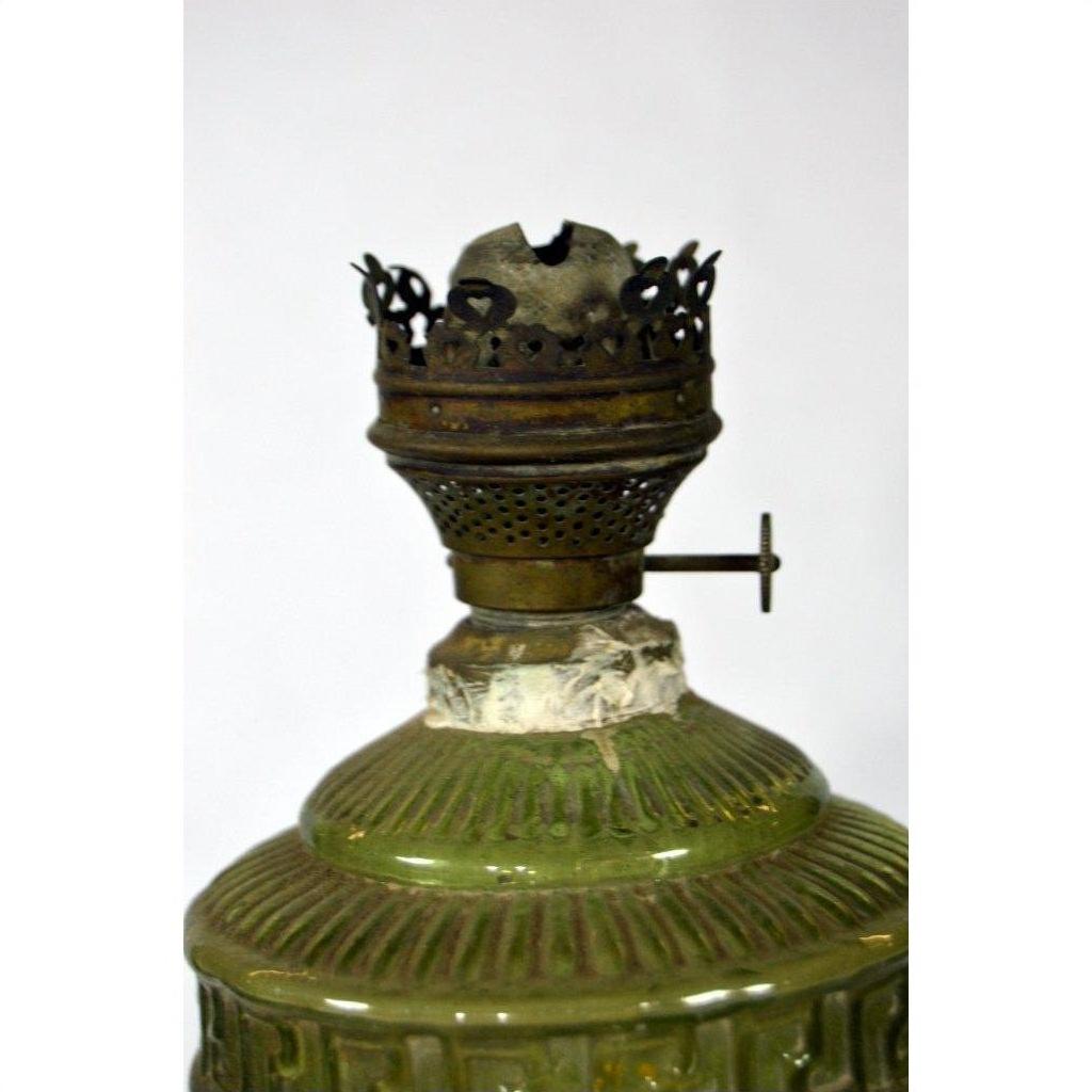 Close-up of green glass oil lamp with metal burner and worn, crown-shaped top, in very good condition.