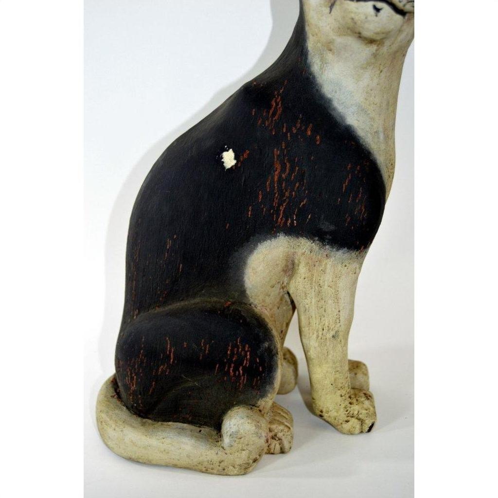Close-up of a black and white hand carved vintage cat statue, wood with worn and chipped areas, in good condition.