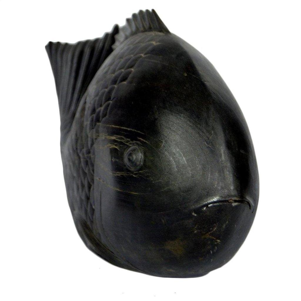 Close-up of dark stone fish sculpture with detailed scales and fins, rounded body, facing slightly right.
