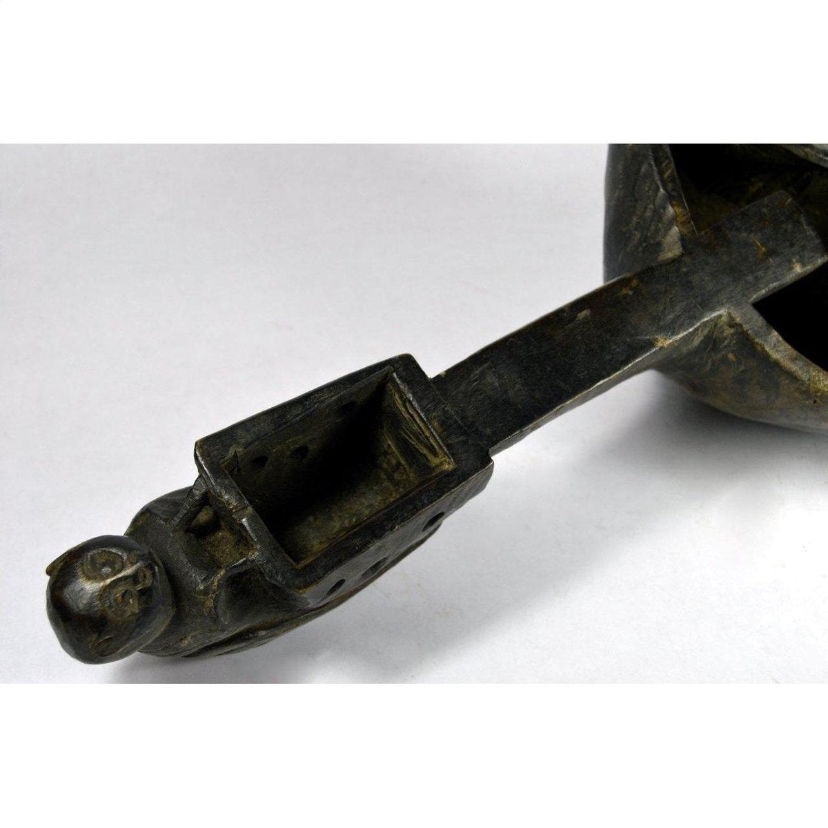 Close-up of a hand-carved metal animal head spout attached to a Saringda lute from Northern India on white background.
