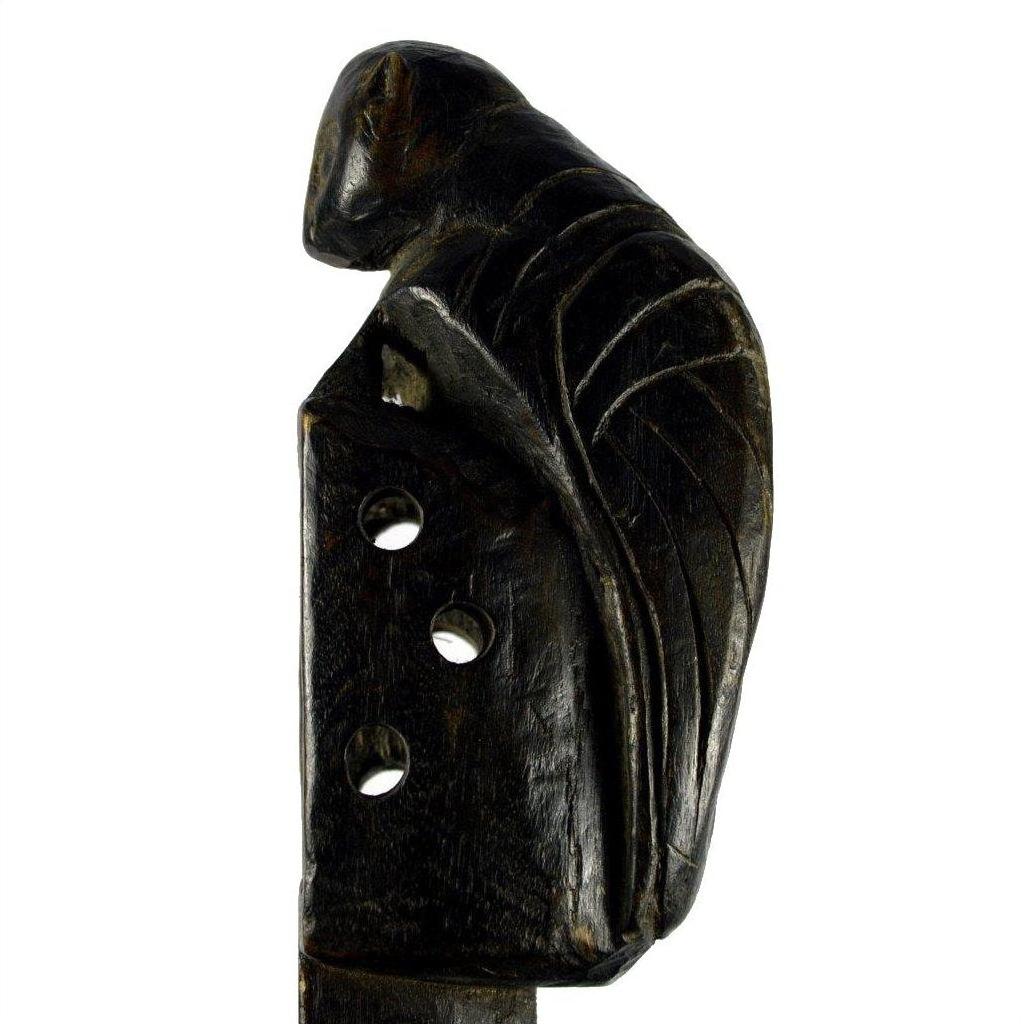 Dark wood carved Indian Saringda lute with a bird figure on top and three holes, folk fiddle, close-up view.