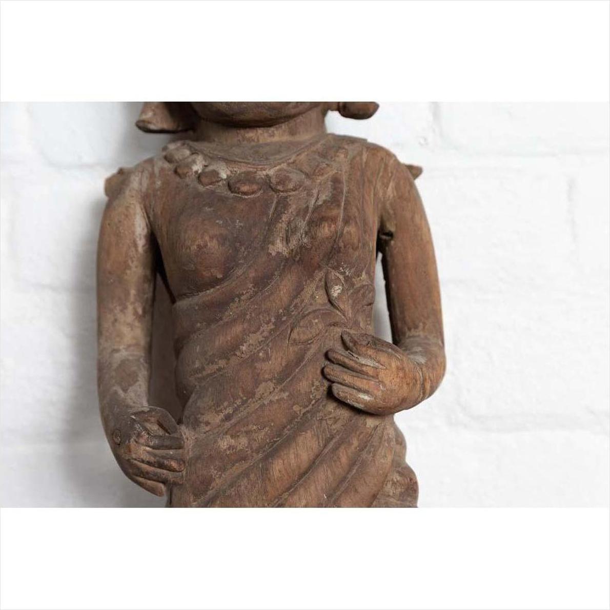 Brown hand-carved wood Hindu deity statue torso, draped hands, close-up, from Gujarat.