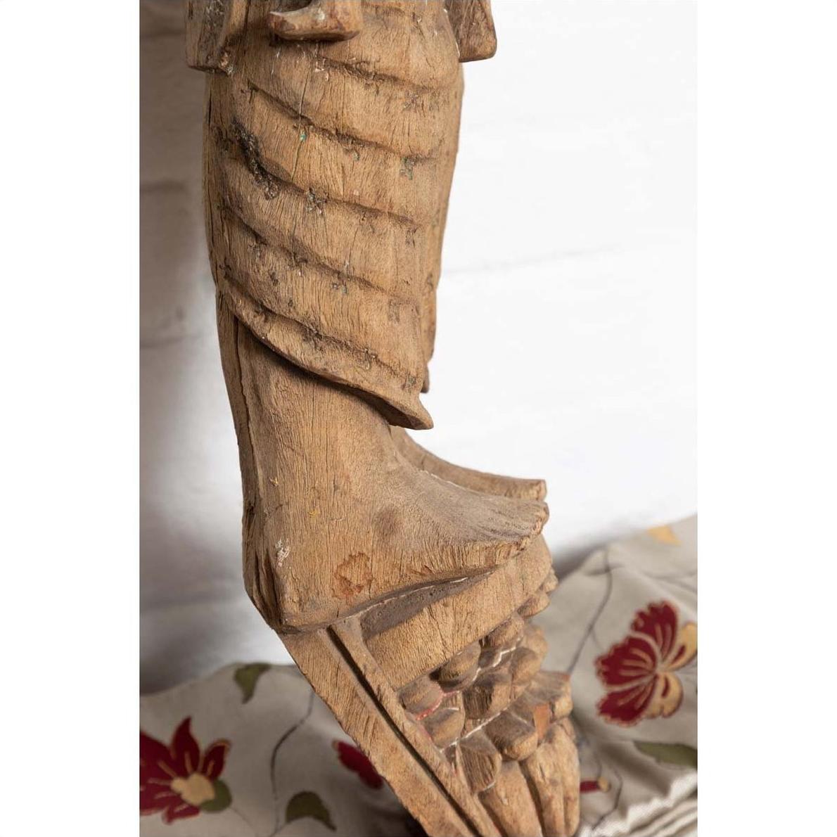 Brown hand-carved wooden statue of Indian mother and child, close-up, on floral fabric background.