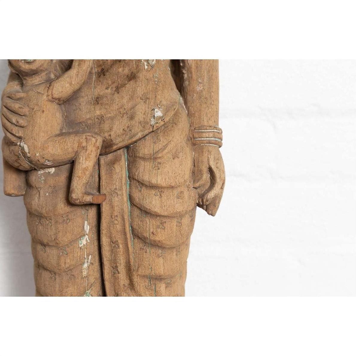 Brown stone statue of mother and child from Gujarat, hand carved with textured worn clothing, close-up.