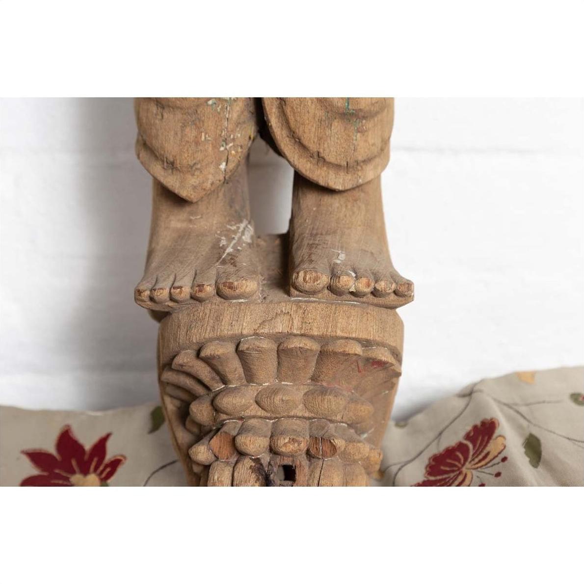 Brown carved stone statue of a mother and child from Gujarat, Indian temple art, indoors.