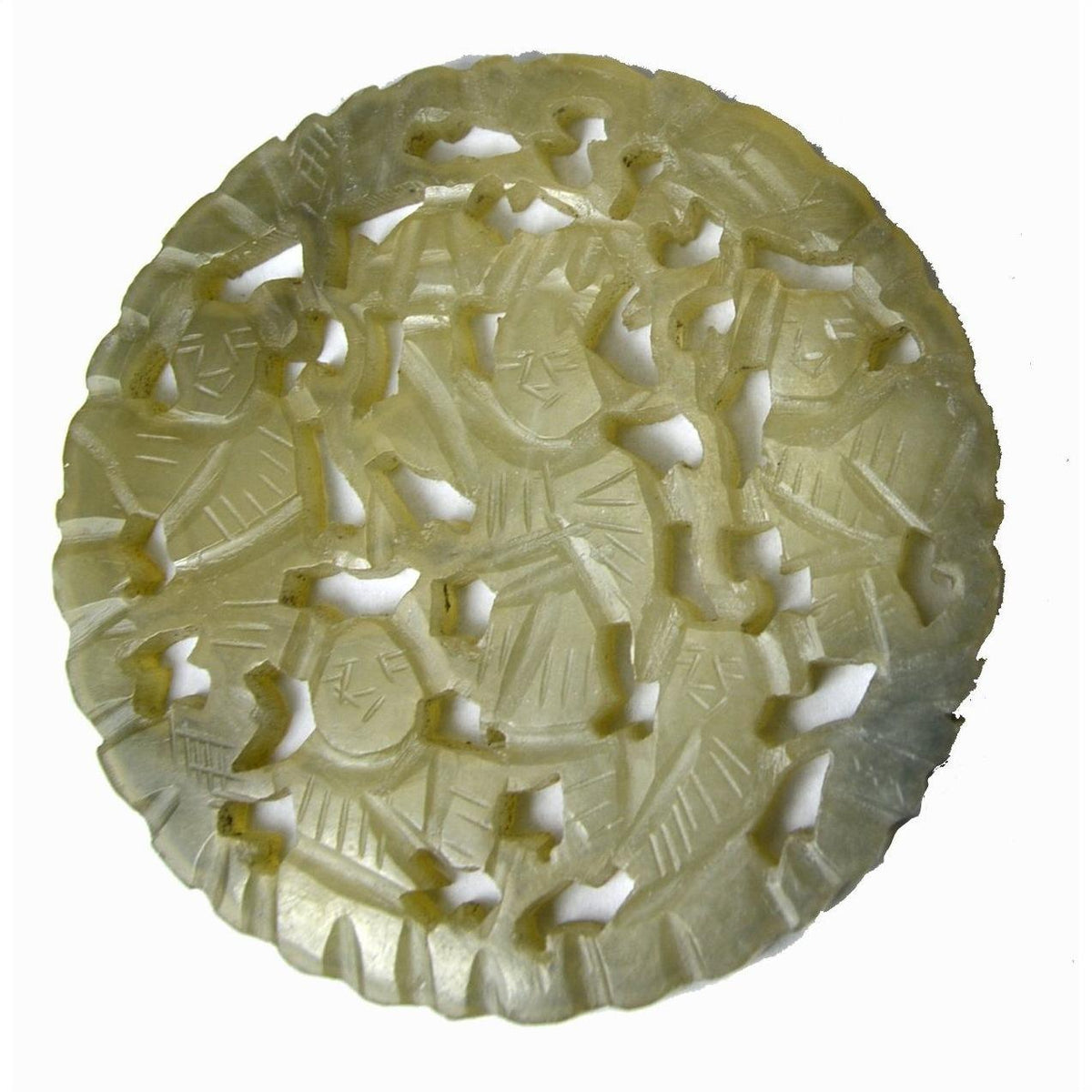 Close-up of green jade medallion with hand-carved robed figures and expressive faces, 2 1/8 inch diameter.