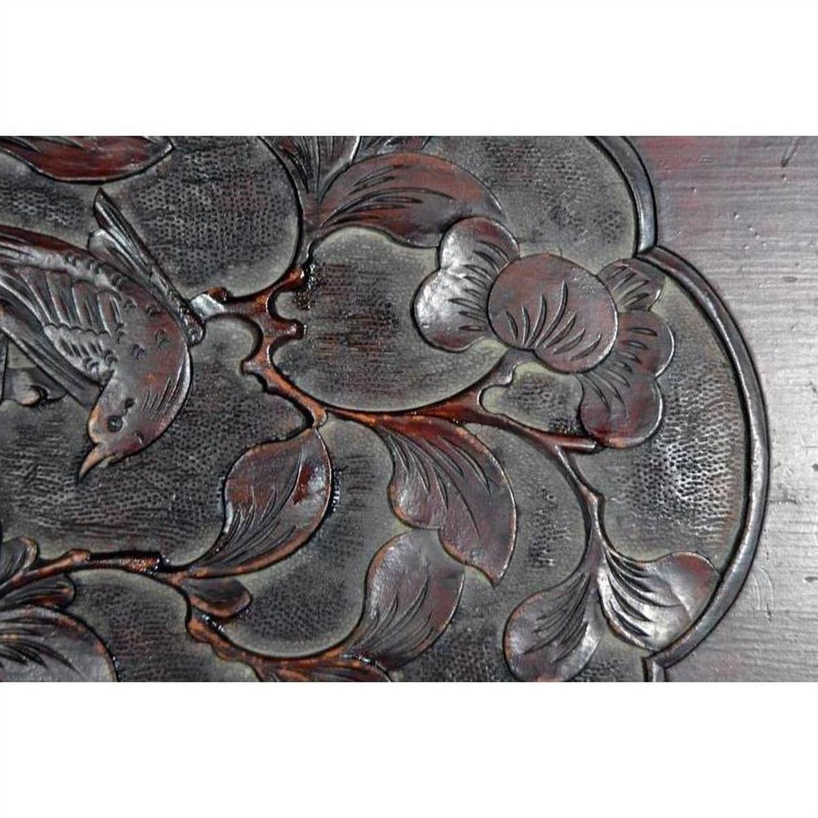 Close-up of a dark rosewood Chinese wall plaque, hand-carved and lacquered with 19th-century bird and floral motifs.