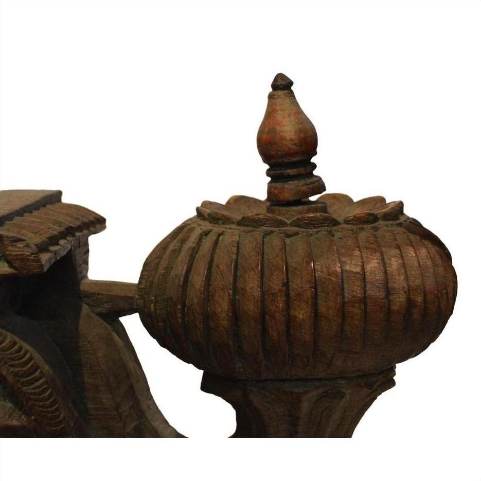 Close-up of brown teak wood architectural element with rounded ribbed design and pointed top.