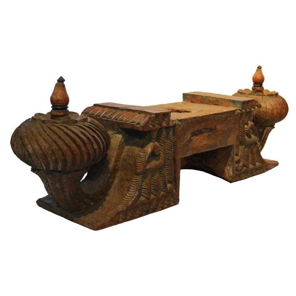 Brown teak wood architectural element with intricate carvings and finials, side view.