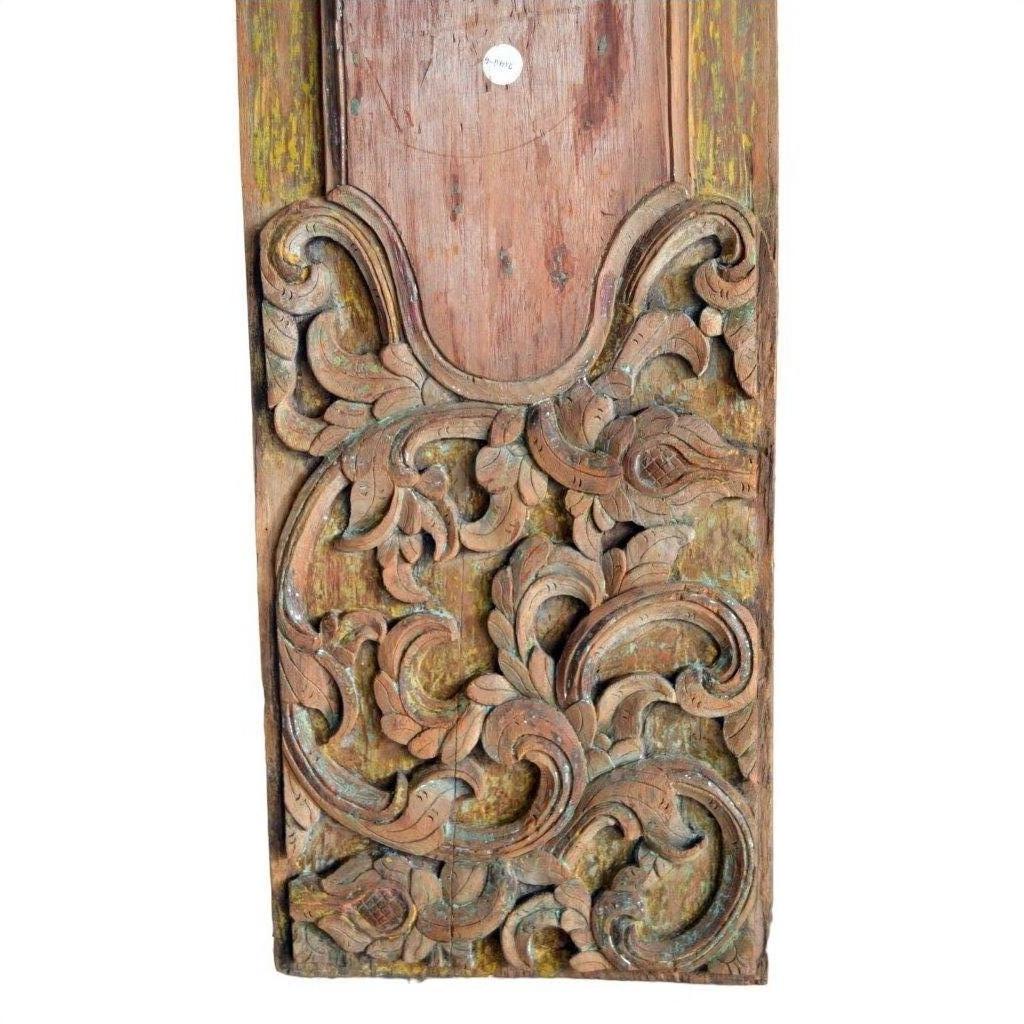 Close-up of weathered wood wall plaques with hand-carved floral and leaf designs in aged tones.