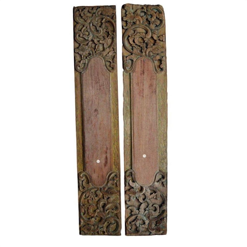 Close-up of two vertical brown wooden wall plaques with ornate hand-carved designs at the top and bottom.