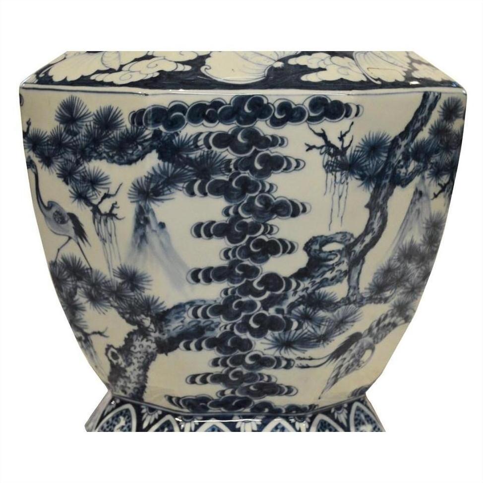 Blue and white porcelain vase with hand-painted pine trees, cranes, and clouds, close-up view.