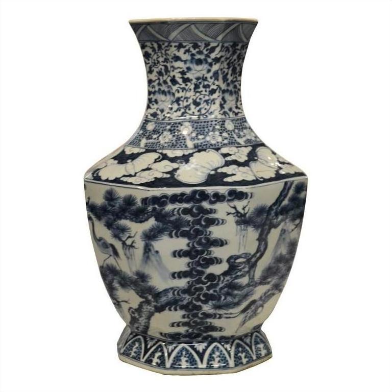Blue and white porcelain vase with hand painted floral motifs, trees, and cloud designs, close-up.