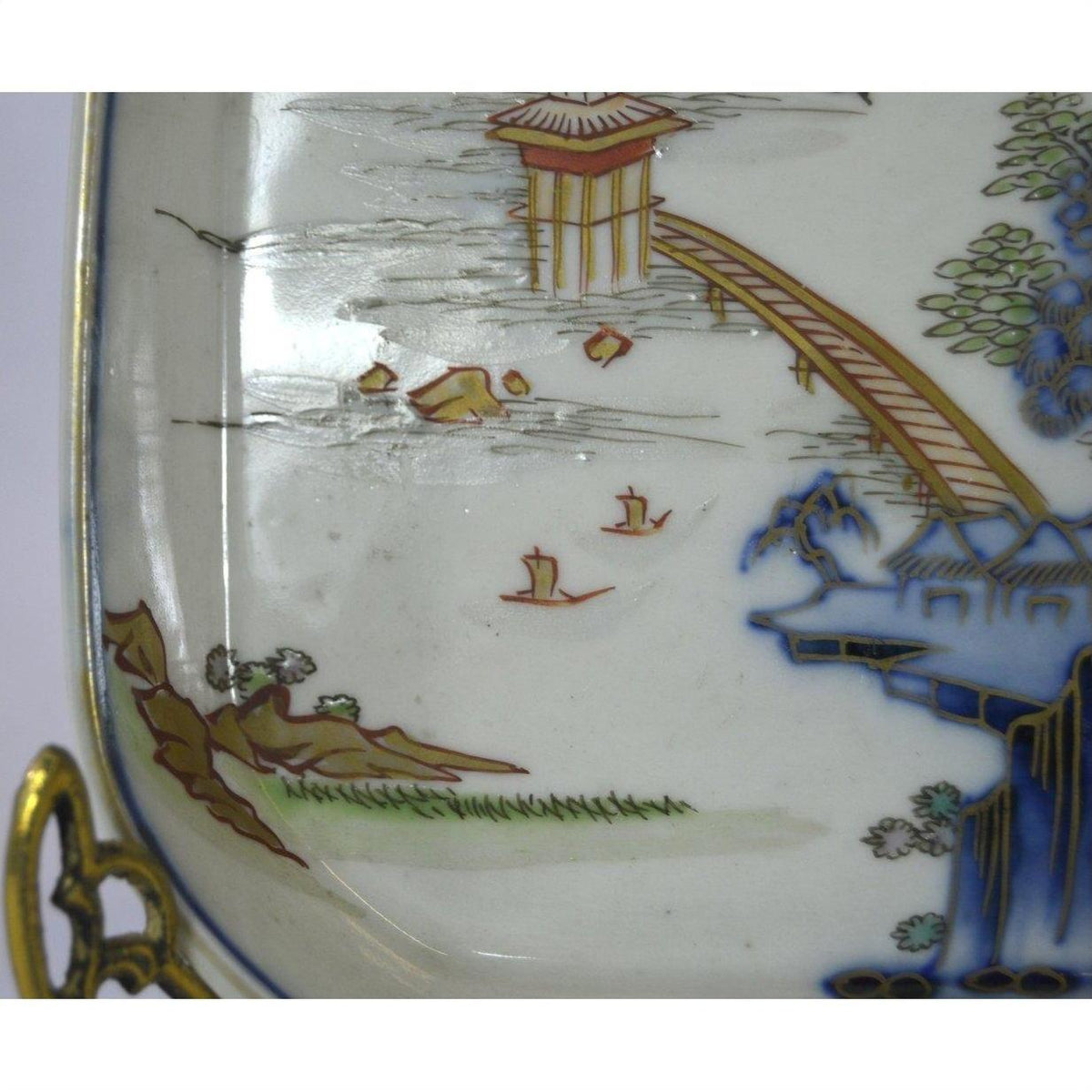 Close-up of a multicolor porcelain Imari bowl with hand painted bridge, water, boats, and landscape design.