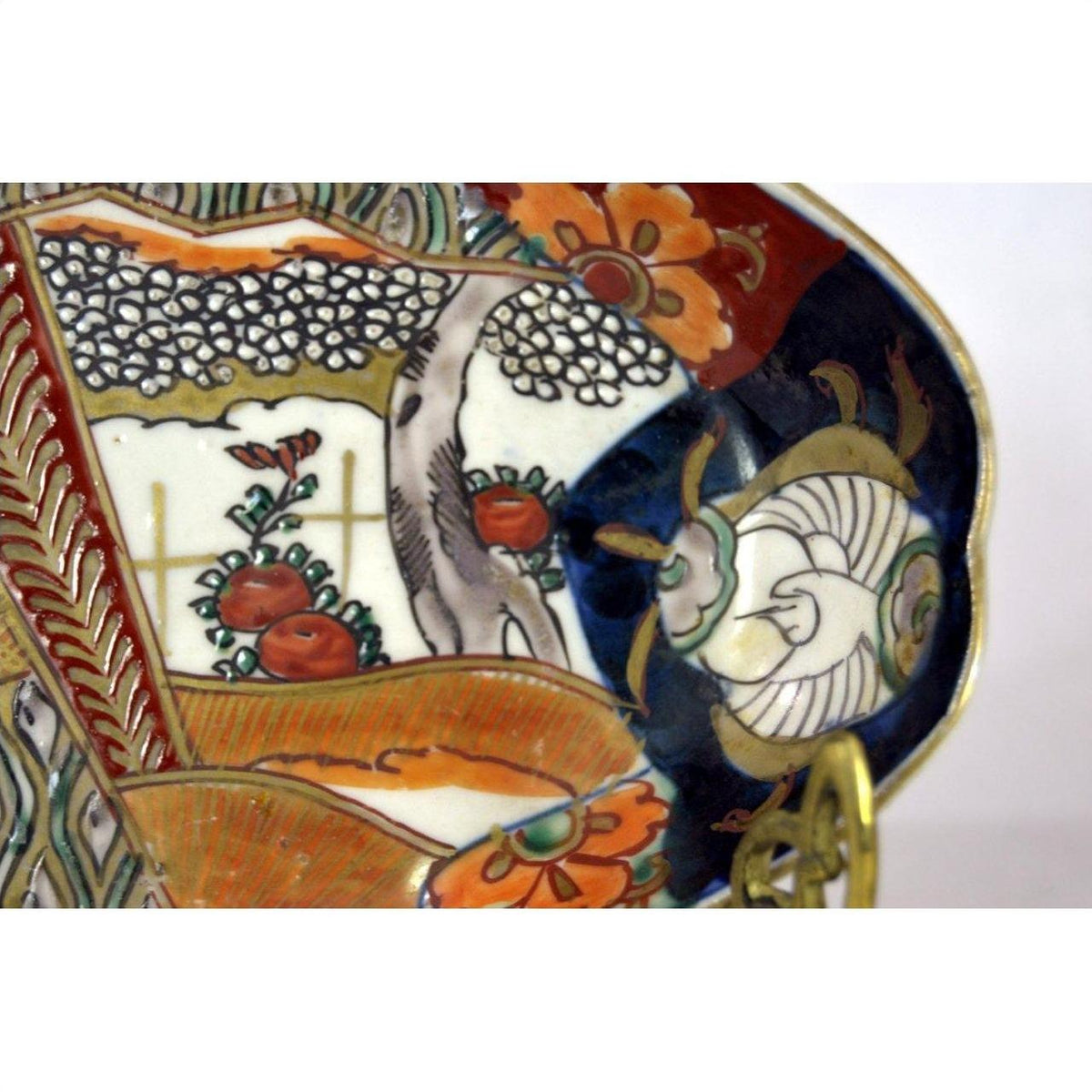 Close-up of a hand painted Imari porcelain plate with red, orange, blue, and gold floral and geometric patterns.