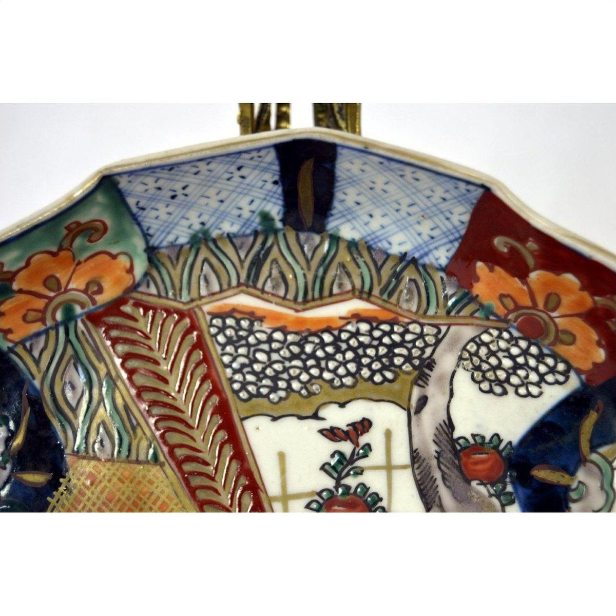 Close-up of a multicolor hand painted porcelain Imari plate with floral and geometric patterns.