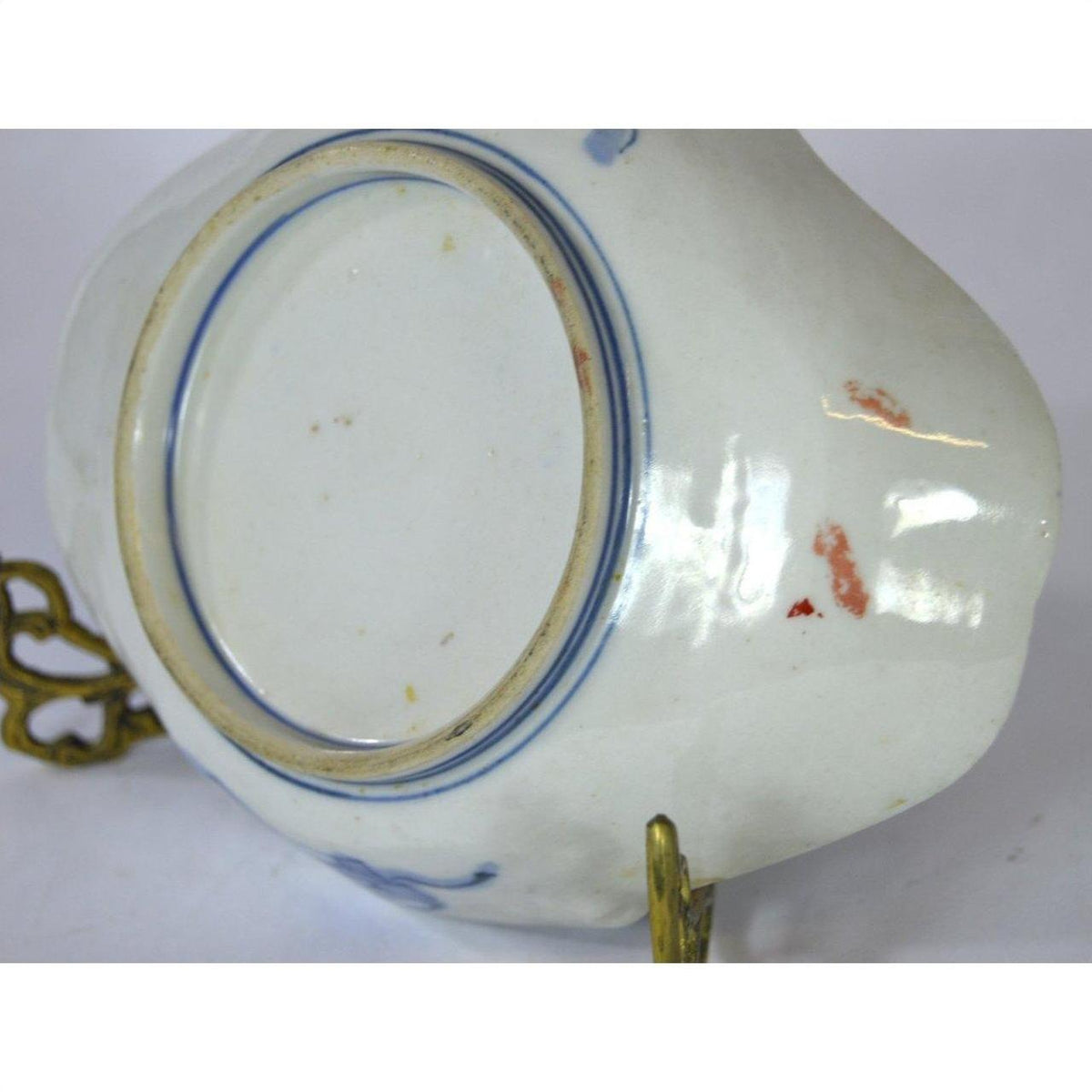 Blue and red porcelain plate with hand-painted accents on a brass stand.