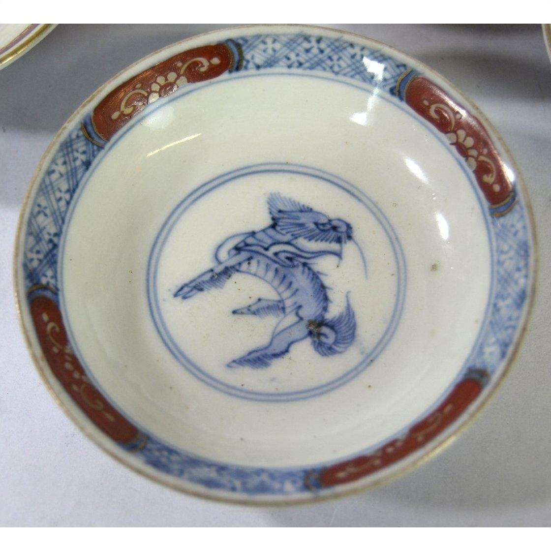 Set of 6 hand painted Imari porcelain small plates with blue mythical center and ornate red and blue rims, close-up.