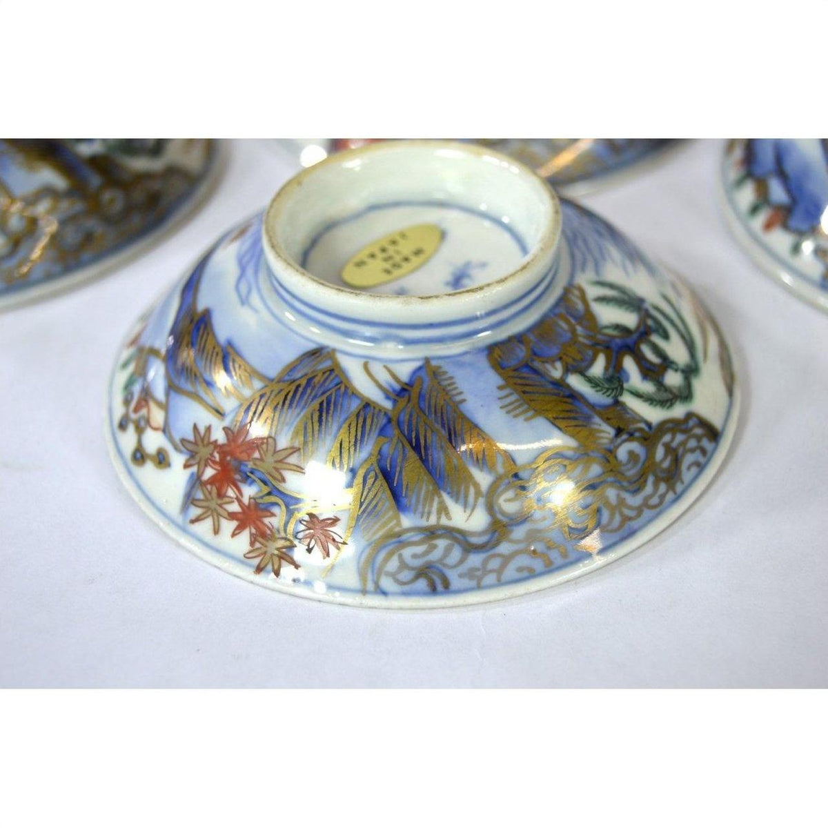 Blue, gold, and red ceramic plate with floral design, shown from the bottom.