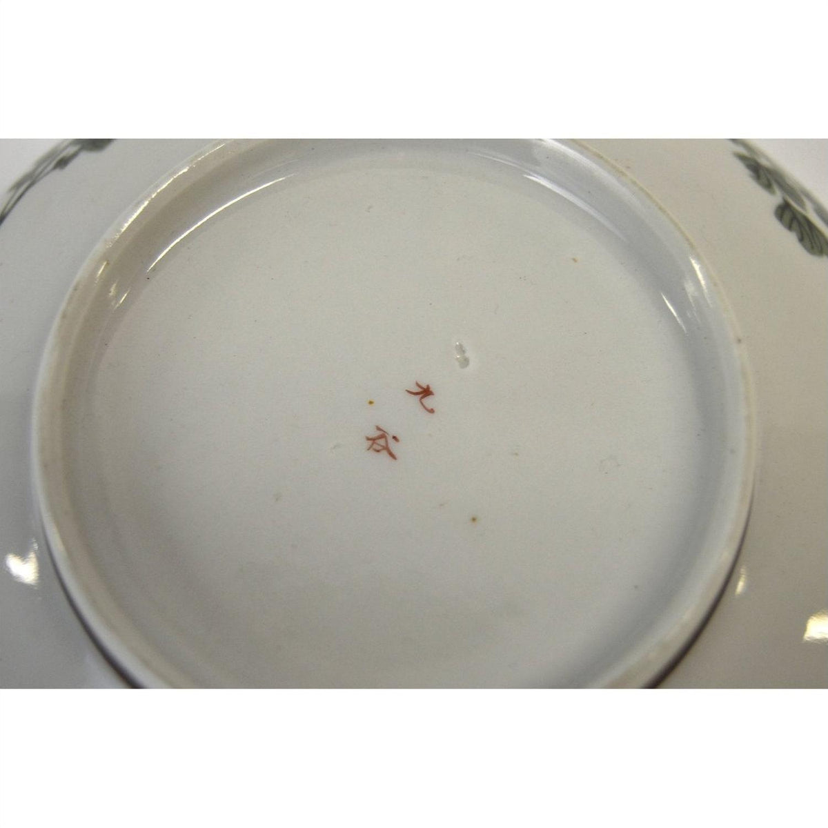 White porcelain bowl with hand painted red Asian characters on base, 7-inch diameter, plain background.