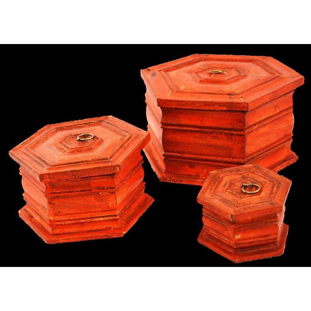 Red-orange hand painted octagonal boxes with metal lid rings, close-up against a black background.