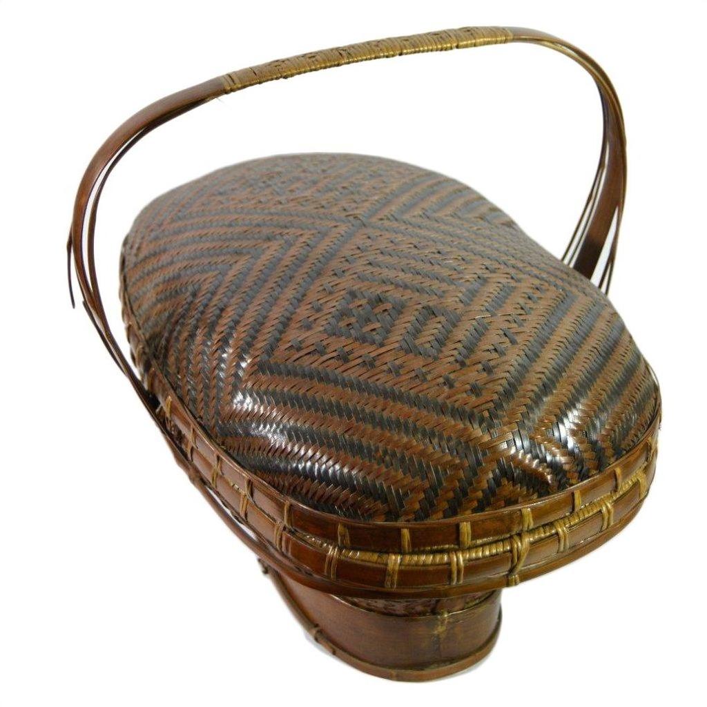 Brown rattan basket with curved handle and geometric patterned lid, hand woven, shown without background.