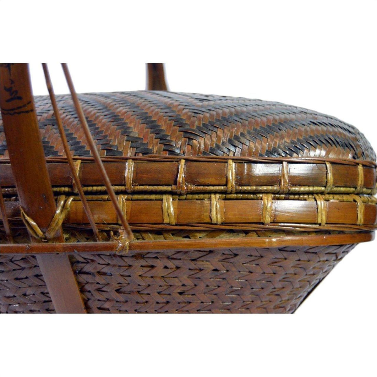 Close-up of a brown and black hand woven rattan basket with intricate zigzag patterns.
