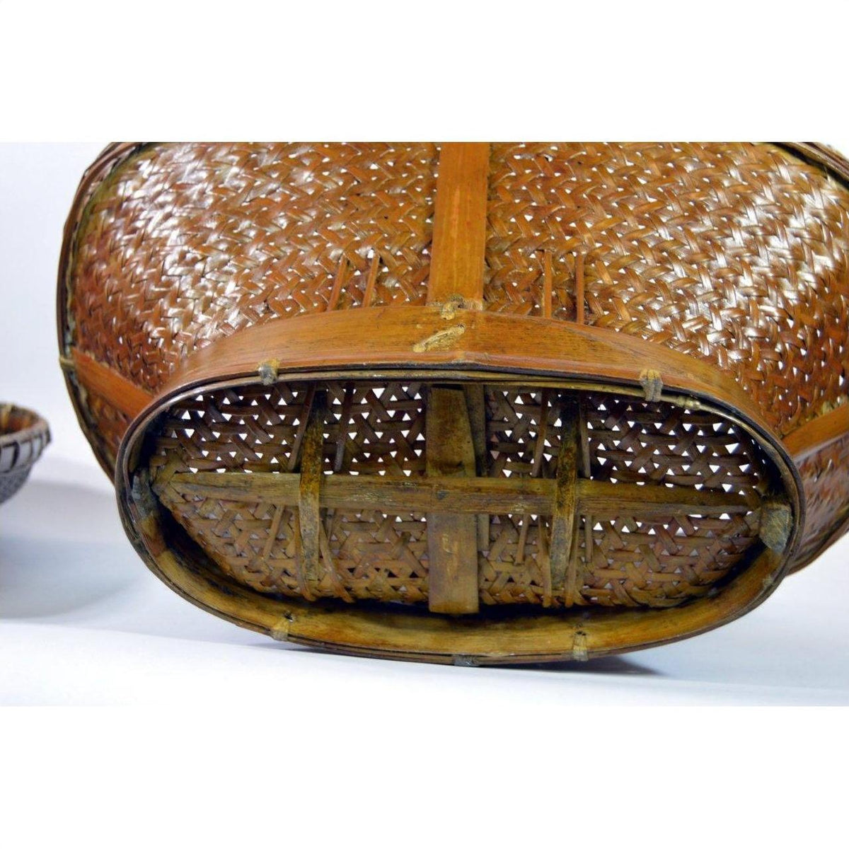 Close-up of brown rattan and wood woven basket bottom with cross supports, showing texture and construction.