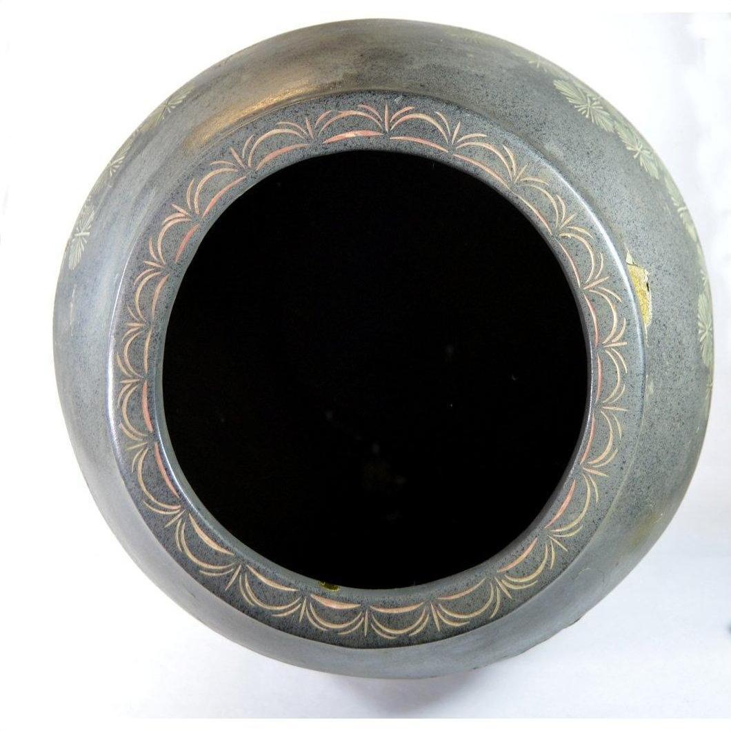 Black clay vase with cracked glaze and worn geometric rim, photographed from above.