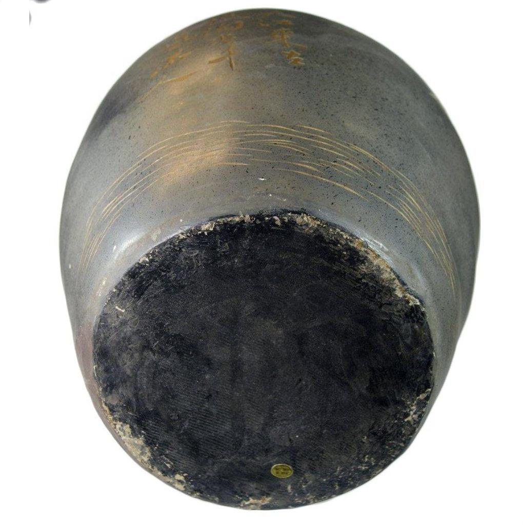 Close-up of a large hand painted vase with cracquelure, circular patterns, and worn edges at the base.