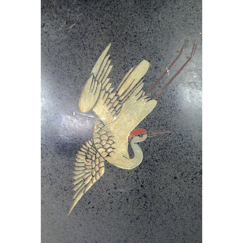 Gold crane with outstretched wings and red crown on dark ceramic vase.