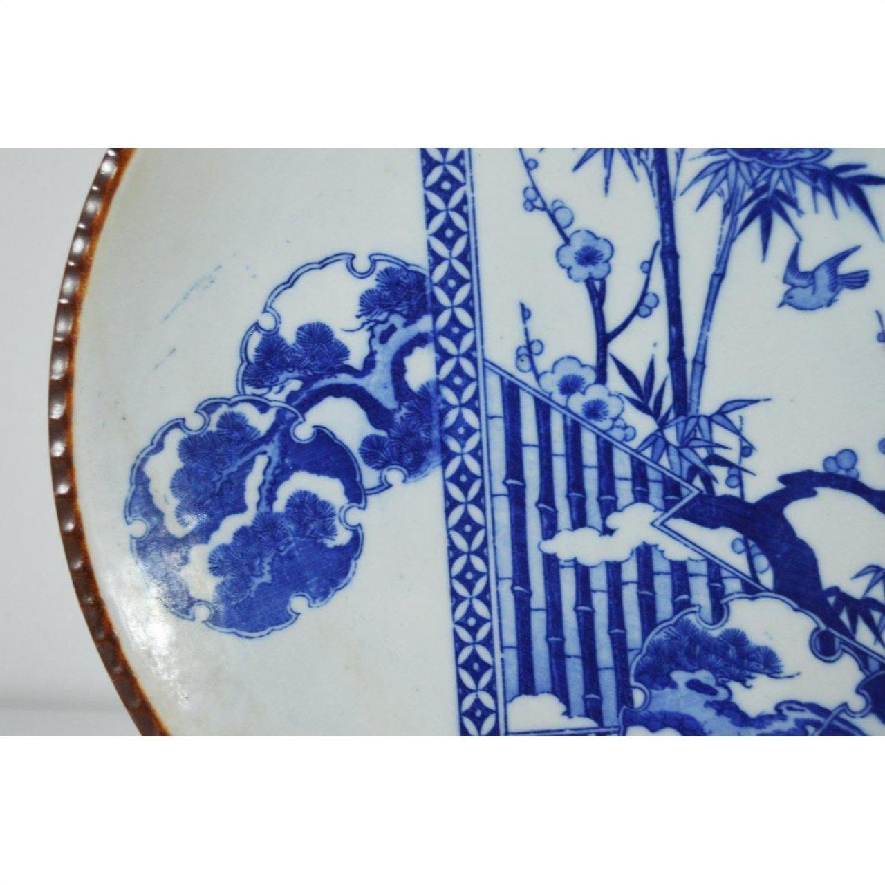 Close-up of white porcelain Igezara plate with floral and bamboo patterns, ridged iron-brown edges.