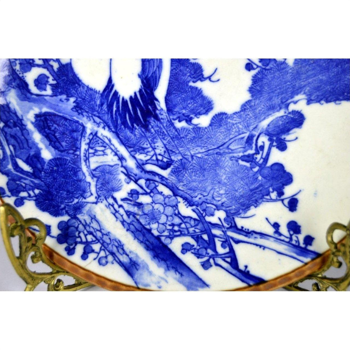 Blue and white Igezara transferware plate with tree and bird motif on ornate gold stand, Meiji period, close-up.