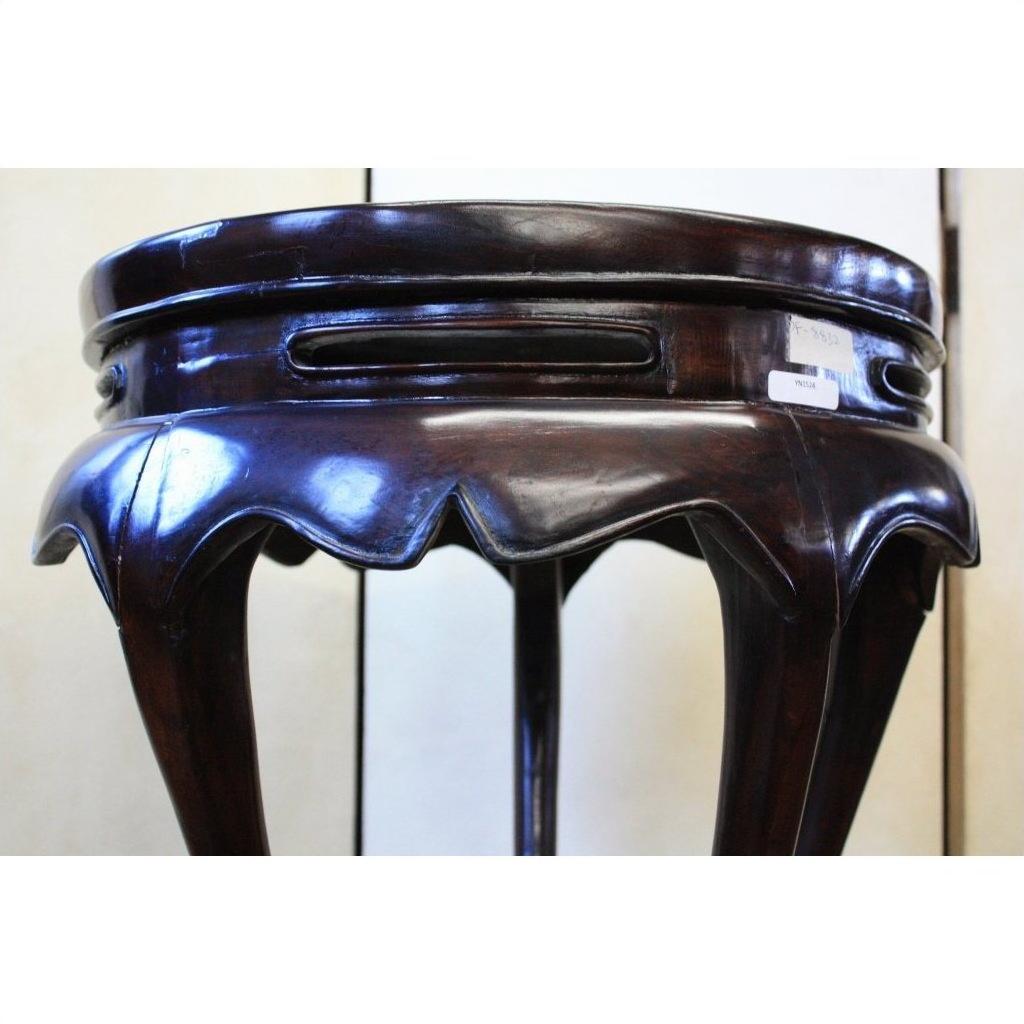 Dark brown lacquer incense stand with scalloped edge and curved legs, low angle view.