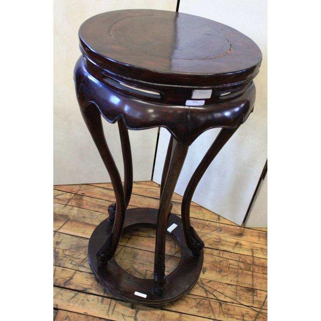 Dark brown lacquered wood incense stand with curved legs on wooden floor, light background, close-up view.