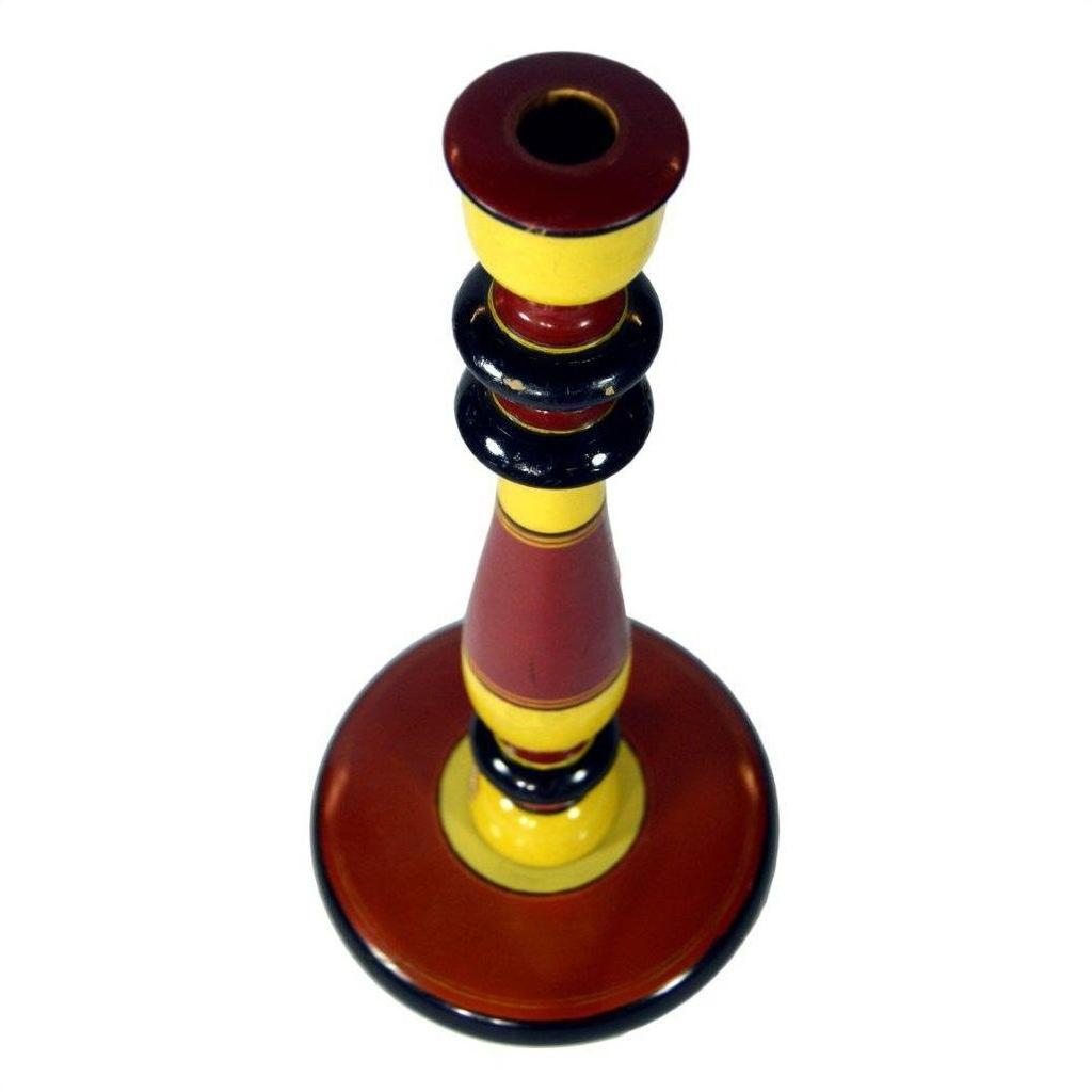 Red, yellow, and black hand-carved wood folk art candlestick, round shape, top view.