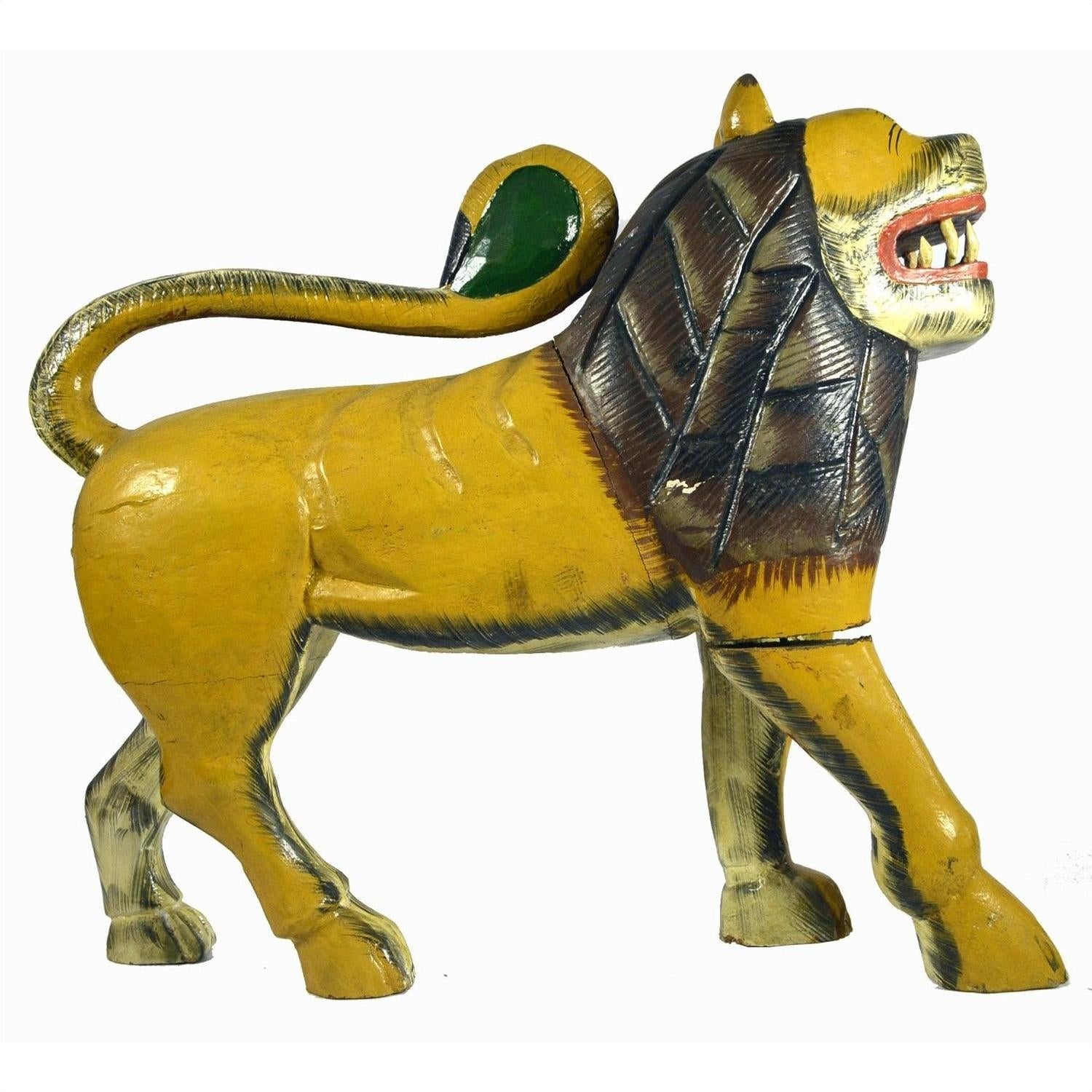 Close-up of yellow hand-carved wooden lion with brown mane, green tail, and open mouth showing teeth, India.