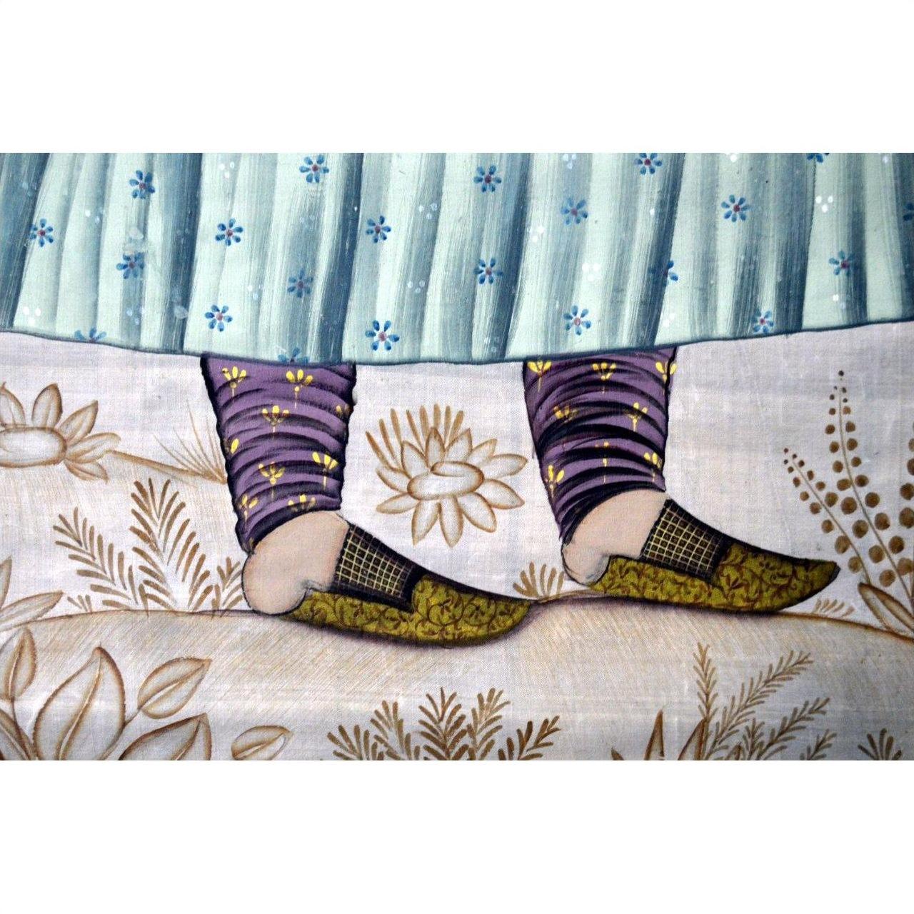 Close-up of patterned slippers on feet wearing purple leggings, resting on an India silk tapestry in very good condition.