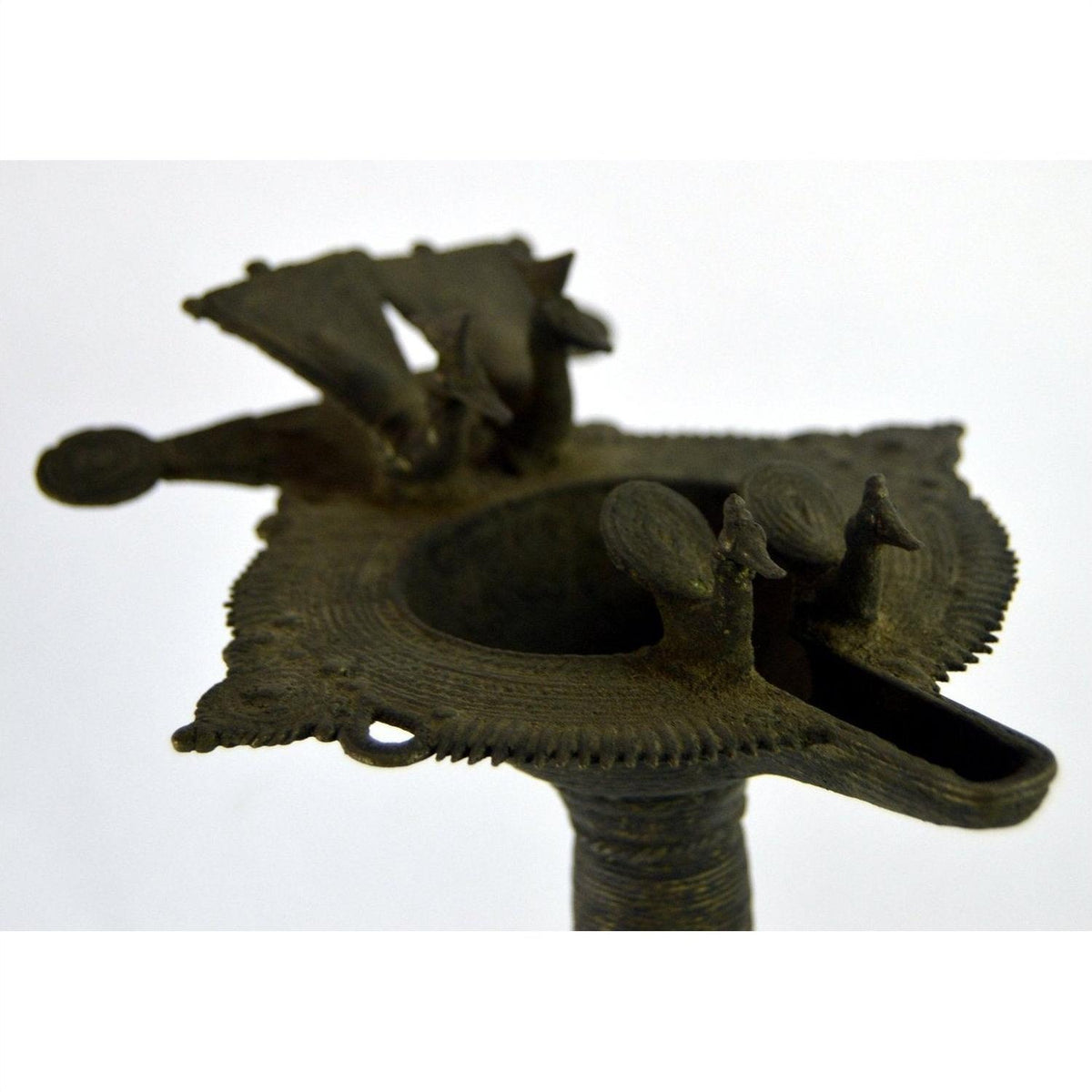 Close-up of brass oil burner with peacock figures, round shape, approximately 5 1/4" diameter.