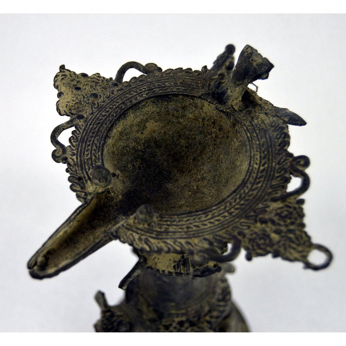 Ornate brass Indian oil burner with intricate details, spout on one side, vase-like design, top view.