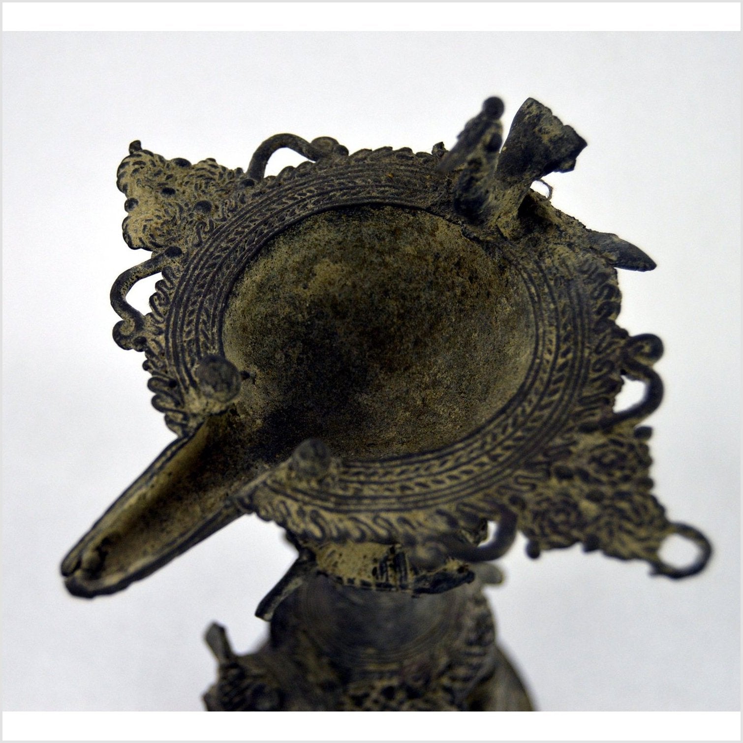 Ornate brass Indian oil burner with intricate details, spout on one side, vase-like design, top view.