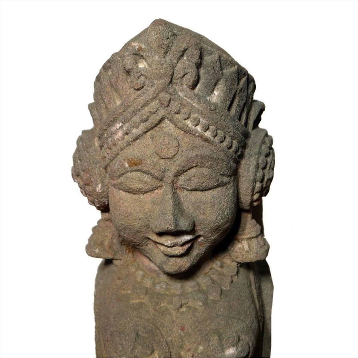 Gray hand-carved stone sphinx sculpture with tiara and earrings, 19th c. Indian, on a white background.
