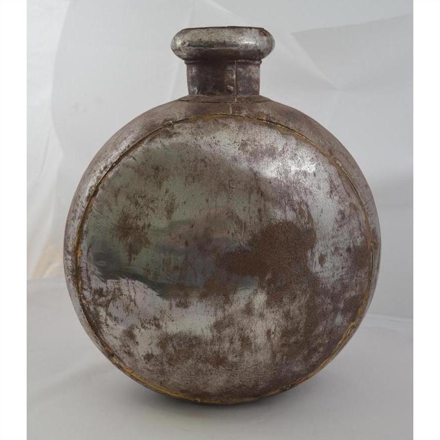 Rustic metal oval-shaped Indian water jug with short neck and cap, close-up on plain white background.