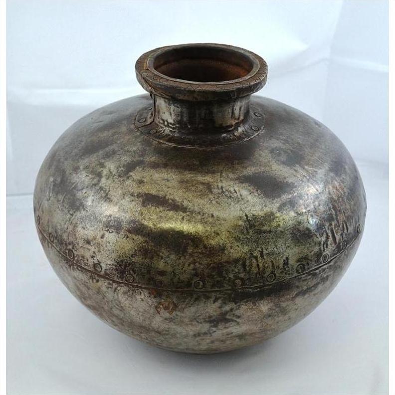 Silver metal antique water jug with round body, narrow neck, and engraved patterns, close-up on white background.